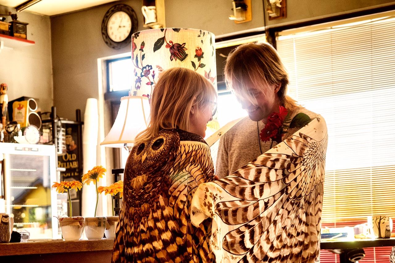 A photo of Ivy and Freyja, wearing owl scarves, looking happy.
